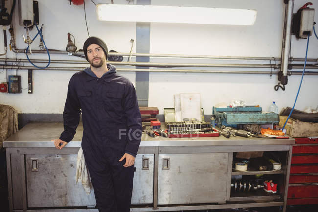 Retrato del joven mecánico de pie en el garaje de reparación - foto de stock