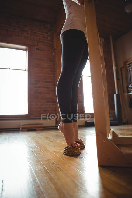 Low section of woman exercising on foot massage ball in fitness studio — Stock Photo