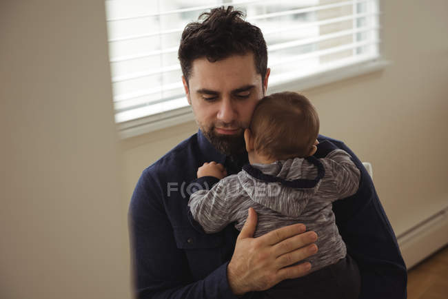 Отец утешает своего маленького сына дома — стоковое фото