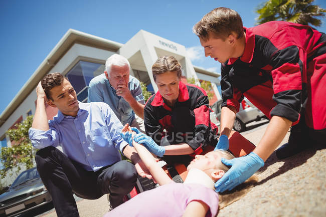 Paramedics examining injured girl on street — Stock Photo