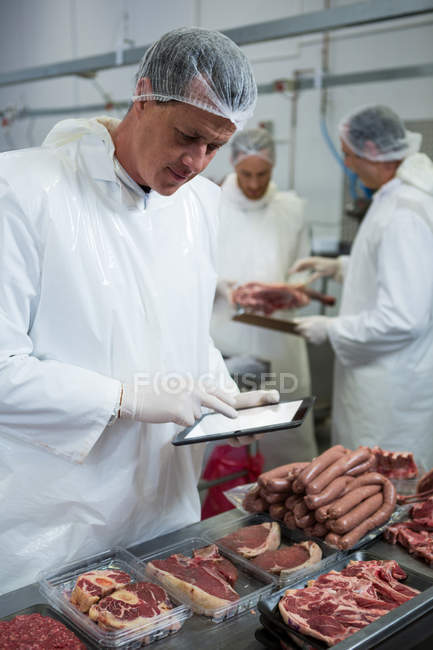 Boucher masculin tenant des dossiers sur tablette numérique à l'usine de viande — Photo de stock