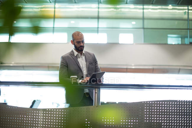 Homme d'affaires utilisant une tablette numérique dans la salle d'attente au terminal de l'aéroport — Photo de stock
