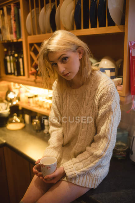 Portrait of woman holding a coffee cup in kitchen at home — Stock Photo