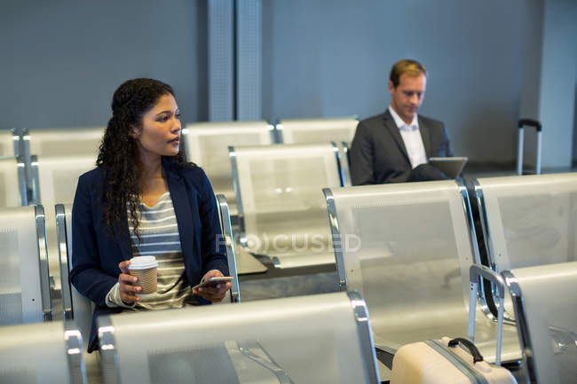 Comutador usando telefone celular na área de espera no terminal do aeroporto — Fotografia de Stock