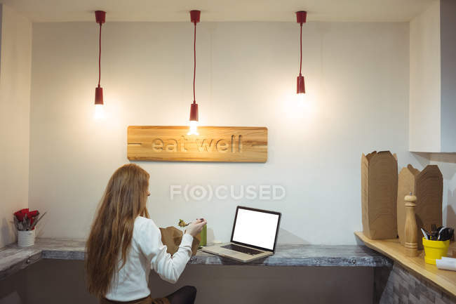 Вид ззаду жінки, що їсть салат в інтер'єрі кафе — стокове фото