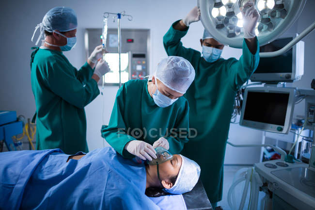 Surgeons adjusting oxygen mask on patient in operation theater of hospital — Stock Photo