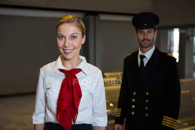 Портрет счастливого пилота и стюардессы, стоящей в терминале аэропорта — стоковое фото