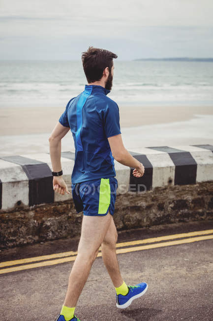 Atleta caminando por la carretera junto a la playa - foto de stock