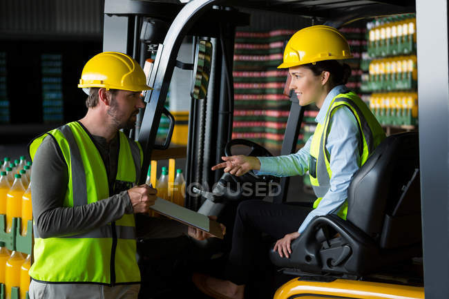 Trabalhador masculino mostrando prancheta para o trabalhador feminino no armazém — Fotografia de Stock