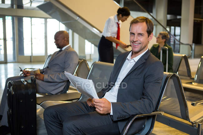 Portrait of businessman reading newspaper in waiting area at airport — Stock Photo