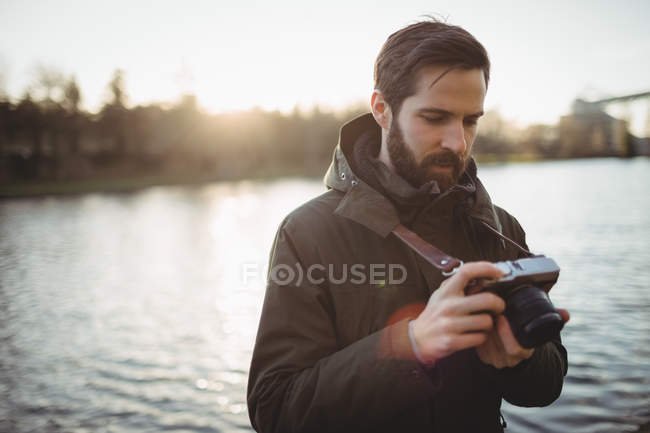 Uomo guardando display sulla fotocamera vicino al lungofiume — Foto stock
