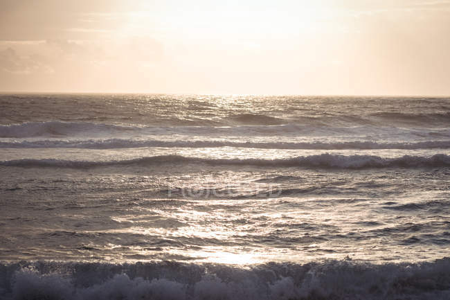 Vagues et réflexion de la lumière du soleil sur la mer au crépuscule — Photo de stock