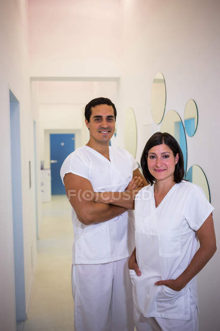 Retrato de dentista masculino y femenino sonriendo en clínica dental - foto de stock