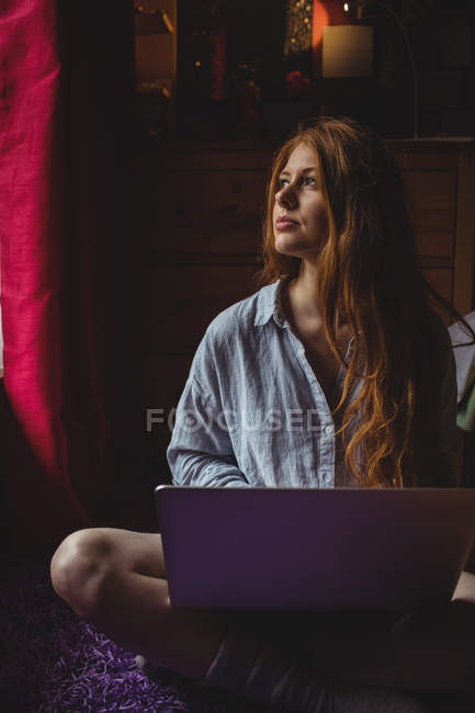 Продумана жінка використовує ноутбук вдома — стокове фото