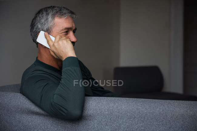 Чоловік говорить на мобільному телефоні у вітальні вдома — стокове фото