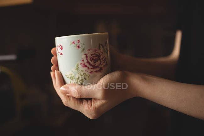 Сегмент жінки, що тримає чашку кави на кухні вдома — стокове фото