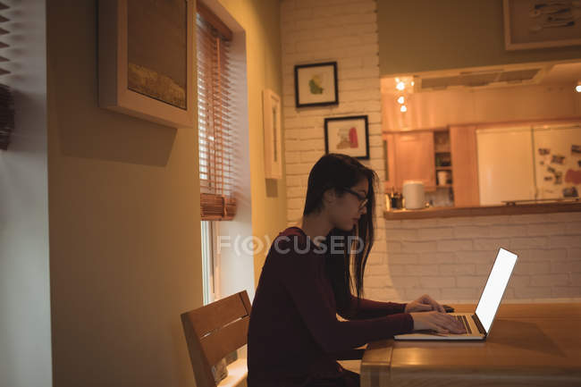 Frau benutzt Laptop auf Tisch im heimischen Wohnzimmer — Stockfoto