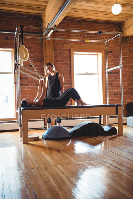 Pilates trainer helping woman while practicing in fitness studio — Stock Photo