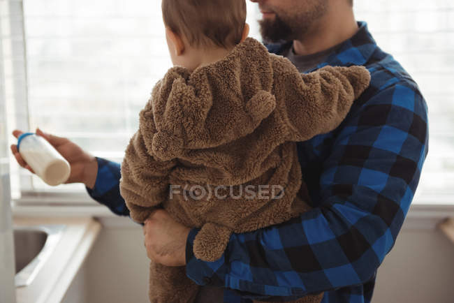 Father preparing milk for baby in kitchen at home — Stock Photo