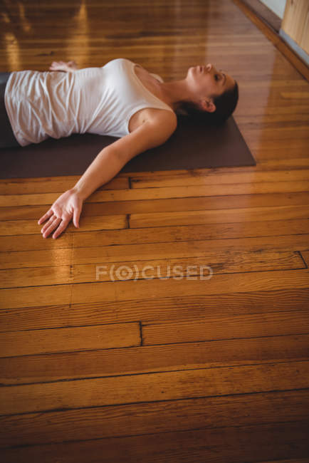 Woman performing yoga in fitness studio on wooden floor — Stock Photo