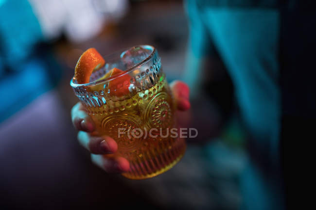 Uomo che tiene un bicchiere di cocktail all'arancia nel bar — Foto stock