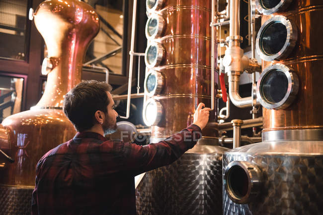 Чоловік регулює клапан контейнера на заводі пива — стокове фото