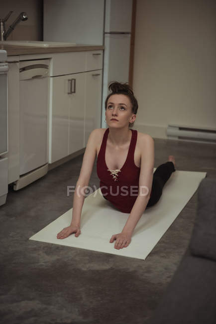 Woman performing yoga in kitchen at home — Stock Photo