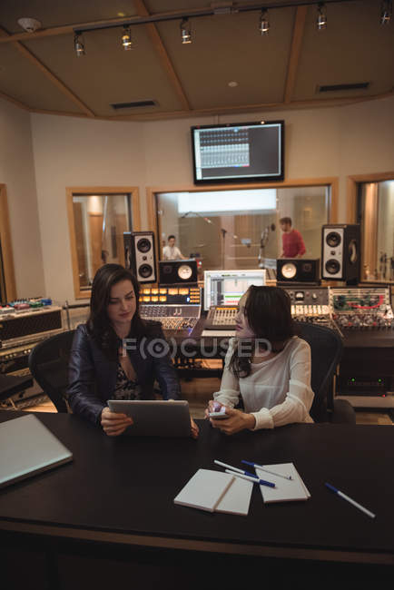 Аудиоинженеры обсуждают друг с другом во время использования цифрового планшета в студии звукозаписи — стоковое фото
