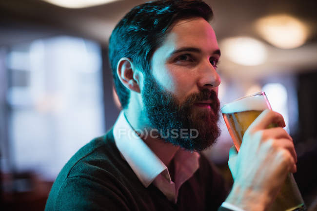 Primer plano del hombre tomando un vaso de cerveza en el bar - foto de stock