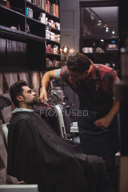 Cliente conseguir barba recortada con tijeras en peluquería - foto de stock