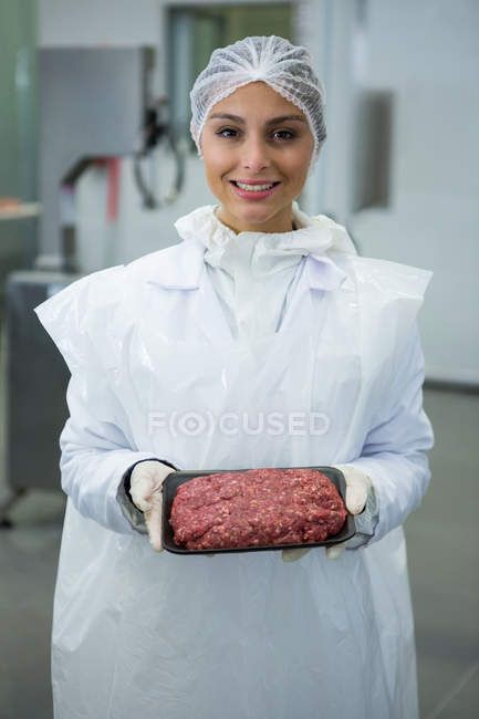 Portrait of female butcher holding tray of minced meat — Stock Photo