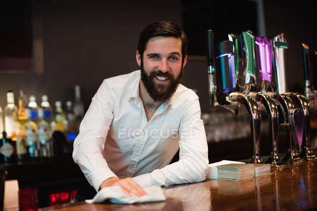 Портрет усміхненого бармена прибирання барної стійки в барі — стокове фото
