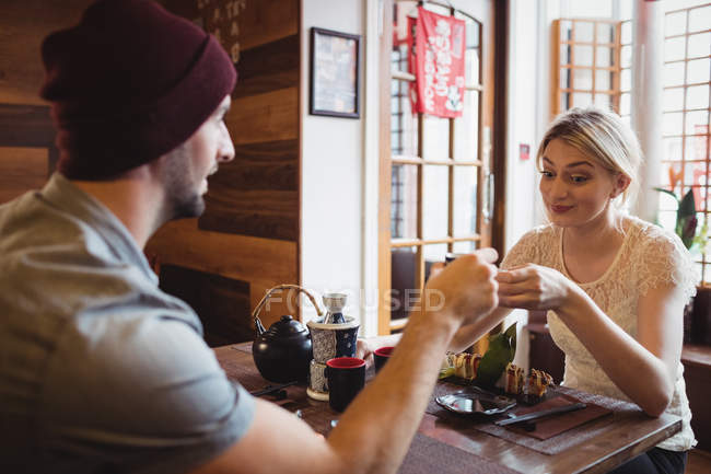 Casal brindar xícaras de saquê enquanto tendo sushi no restaurante — Fotografia de Stock