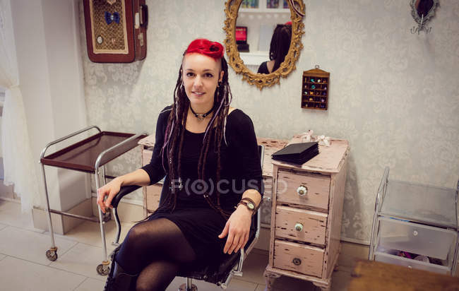 Портрет жінки-перукаря, що сидить у магазині дредлоків — стокове фото