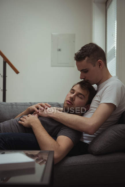 Романтична гей пара розслабляється на дивані у вітальні вдома — стокове фото