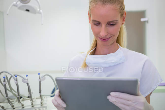 Dentista femenina usando tableta digital en la clínica - foto de stock