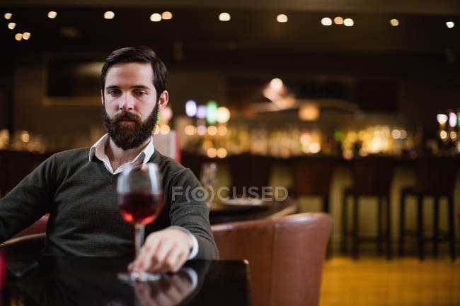 Uomo guardando un bicchiere di vino rosso nel bar — Foto stock