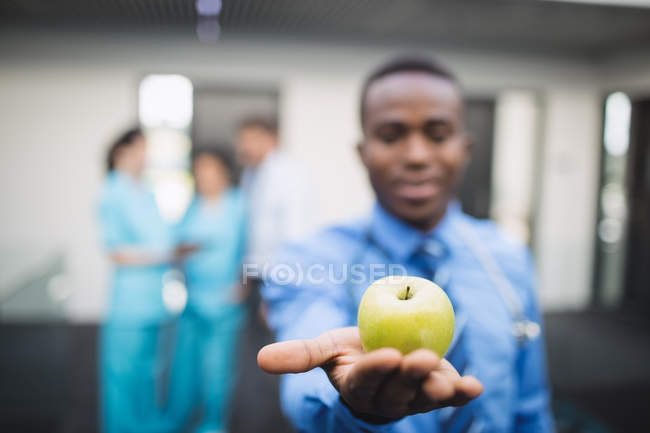 Крупним планом лікар показує зелене яблуко в лікарняному коридорі — стокове фото