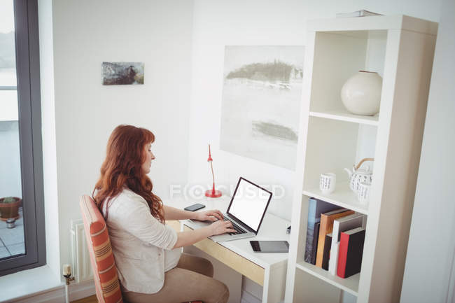 Femme enceinte utilisant un ordinateur portable dans la salle d'étude à la maison — Photo de stock