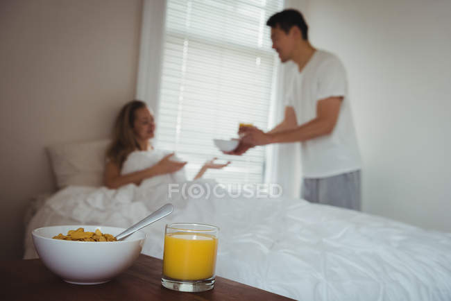 Petit déjeuner et jus de fruits sur la table dans la chambre à coucher à la maison — Photo de stock