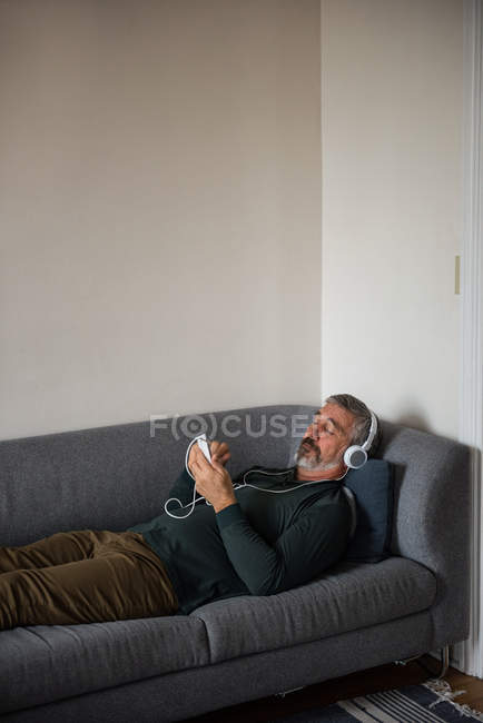 Man listening music on mobile phone at home — Stock Photo