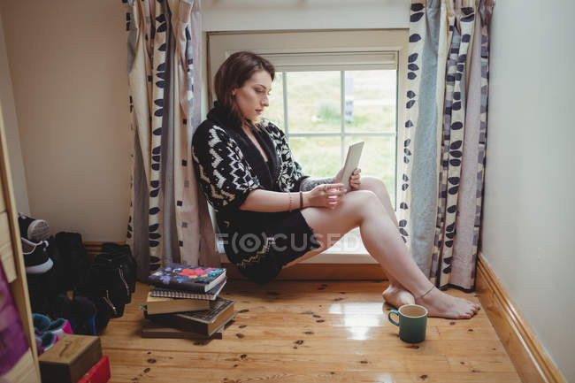 Жінка сидить на підвіконня і на дому за допомогою цифровий планшетний — стокове фото