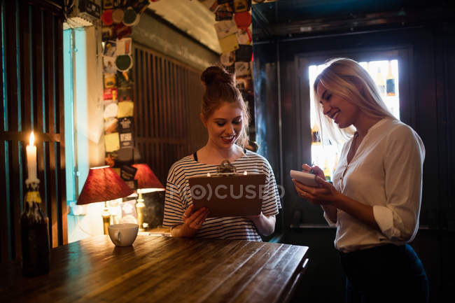 Camarera discutiendo el menú con el cliente en el bar - foto de stock