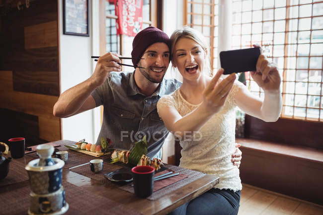 Casal tomando selfie enquanto tendo sushi no restaurante — Fotografia de Stock
