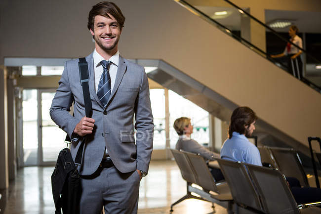 Retrato del hombre de negocios parado en la sala de espera en el aeropuerto - foto de stock