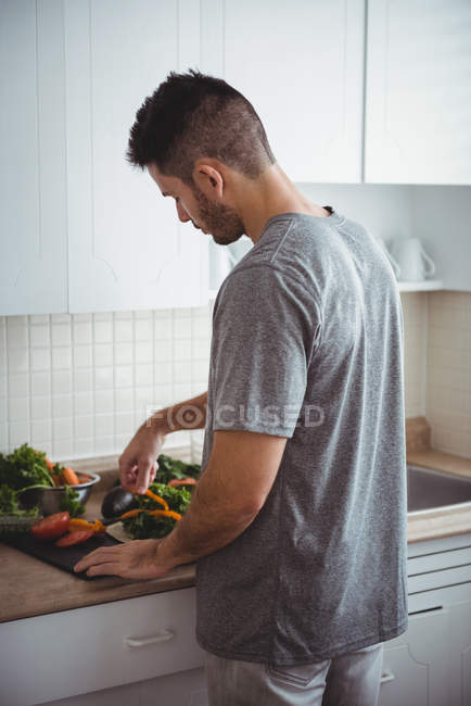Man placing a bell pepper on burrito in the kitchen at home — Stock Photo