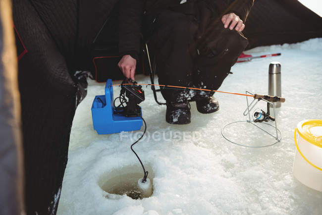 Partie médiane d'un pêcheur sur glace installant un canard à glace — Photo de stock