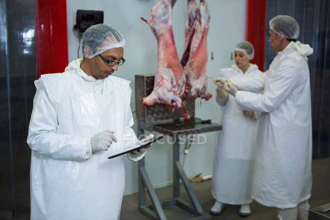 Técnico usando tableta digital en la fábrica de carne - foto de stock