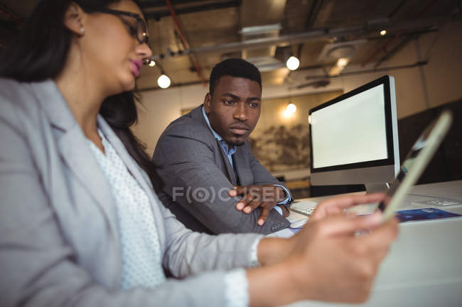 Бизнесмен и коллега обсуждают за цифровым планшетом в офисе — стоковое фото