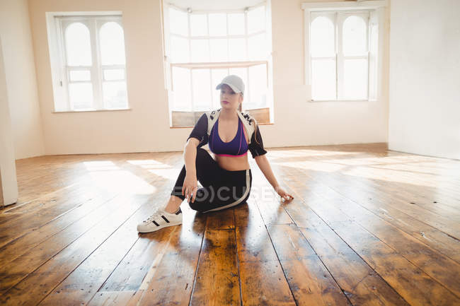 Junge hübsche Frau sitzt auf Hartholz im Studio — Stockfoto